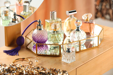 Different luxury perfumes on wooden dressing table indoors