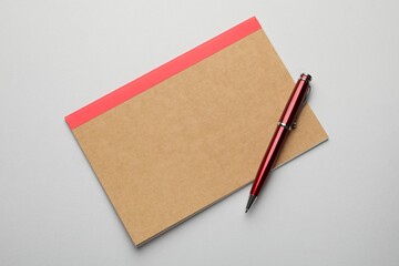 Copybook and pen on grey background, top view
