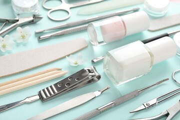 Set of different manicure tools and flowers on turquoise background, closeup
