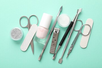 Naklejka premium Set of different manicure tools on turquoise background, flat lay