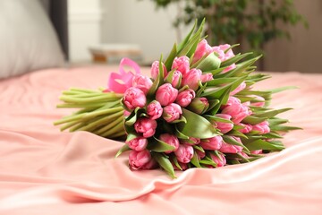 Bouquet of beautiful tulips on bed indoors