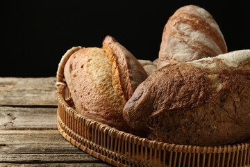 Different loaves of fresh bread in basket on wooden table, closeup
