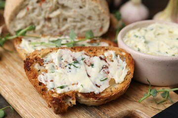 Tasty bread with garlic, herbs and oil on wooden table, closeup