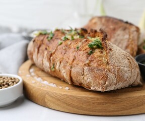 Tasty bread with garlic, herbs and oil on white table, closeup