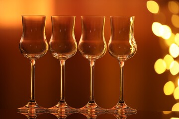 Many clean glasses on glass mirror surface against blurred lights. Bokeh effect