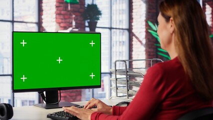 Independent person using computer with green screen for remote job tasks at home setup, surrounded...