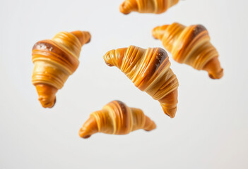 Croissant floats in mid-air, highlighting its buttery golden layers against a clean white background, evoking a sense of lightness and delight.