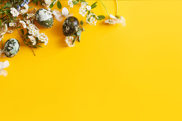 Happy Easter! Modern dyed eggs and spring blossom flat lay with space for text on yellow background. Easter banner, poster template
