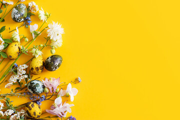 Happy Easter! Modern dyed eggs and spring blossom flat lay with space for text on yellow background. Easter banner, poster template