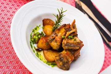 Appetizing baked rabbit meat with garlic served with potatoes on plate
