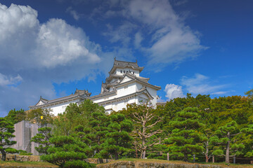 Himeji, Japan - Sep 24 2024, Panoramic view of Himeji Castle, White Heron Castle with trees and plants of park on foreground, at daytime with blue cloudy sky, without people, Himeji, Japan