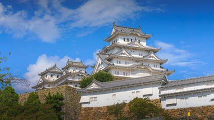 Himeji, Japan - Sep 24 2024, Panoramic view of Himeji Castle, White Heron Castle with trees and plants of park on foreground, at daytime with blue cloudy sky, without people, Himeji, Japan