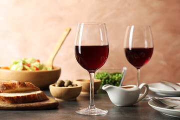 Red wine and delicious dinner served on grey table