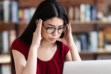 Asian Nerd Student Girl Studying Online With Laptop In Cafe, Touching Temples, Trying To Concentrate, Preparing For Difficult Exam