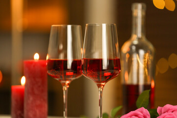 Glasses of red wine against blurred background, closeup. Romantic dinner