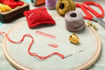 Embroidery. Canvas with cross stitches and supplies on table, closeup