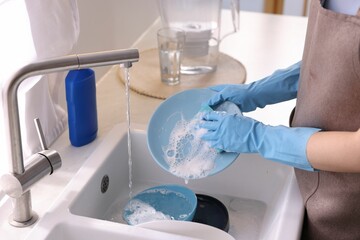Woman washing dishes in kitchen sink, closeup