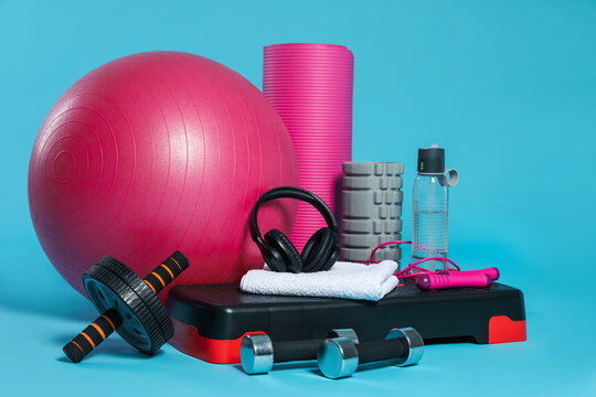 Different fitness equipment and headphones on light blue background