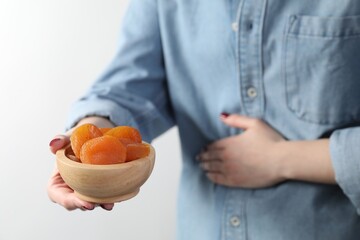 Woman refusing to eat dried apricots on white background, closeup. Food allergy concept