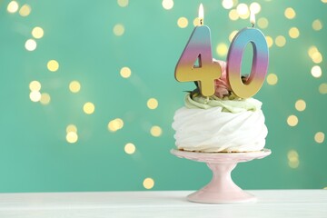 40th birthday. Tasty cupcake with burning number shaped candles on white wooden table against turquoise background with blurred lights, space for text. Bokeh effect