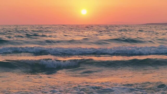 Cinematic tripod shot of sea waves gently crashing on the shore during a golden sunset. Warm reflections of pink and orange hues create a calm, romantic mood. Travel, nature, relaxation, inspiration