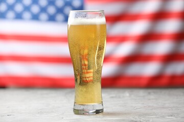 Glass of beer on grey table against American flag