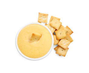 Tasty cheese dipping sauce in bowl and crackers isolated on white, top view