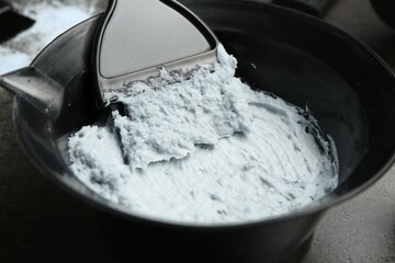 Mixing hair bleaching powder and developer on grey background, closeup