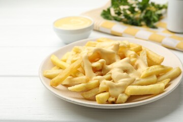 French fries with cheese sauce and parsley on white wooden table, closeup