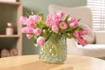 Beautiful tulips in vase on wooden table indoors, closeup