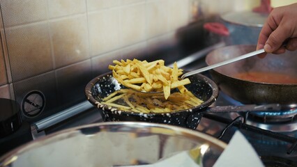  Chef's Hand Drains Spicy French Fries from Boiling Oil to Place in Paper Towels