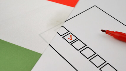Hand marks box with red marker on ballot. Democratic elections in Italy. National flag of Italian Republic in background. Transparent voting process reflects civic engagement in political decisions