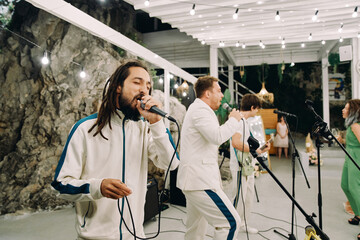 Paris, France - April 28, 2024: Musical group performs on stage under a canopy with glowing garlands of light bulbs