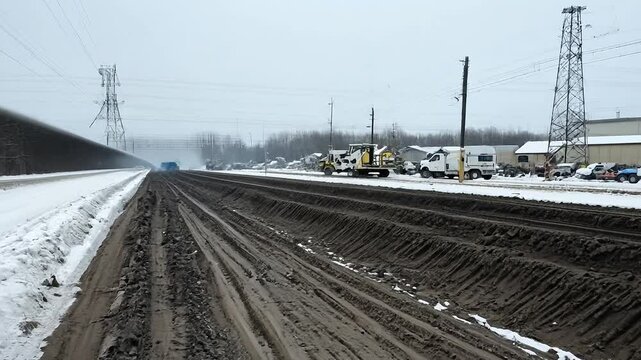 Snow-covered road with muddy tire tracks and power lines running through winter forest landscape under overcast sky. Cold weather and transportation concept. Design for wallpaper, banner, poster. Pers