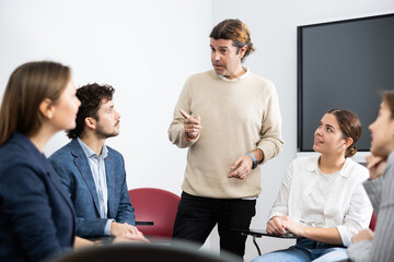 Experienced male teacher giving lecture to group of student