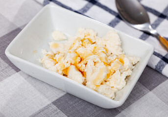 Portion of traditional Catalan dessert, mato with honey, served on table.