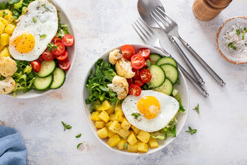 Healthy breakfast bowl with cooked potatoes, raw vegetables and fried egg