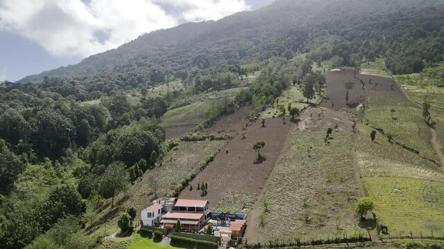 Drone flies backwards from basecamp to reveal the entire Acatenango Volcano in Guatemala on partially cloudy morning