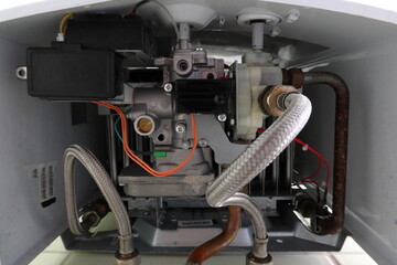 Close-up view of the internal components of a gas water heater. Pipes, wires, and metal parts of the heating system used to supply hot water in a home