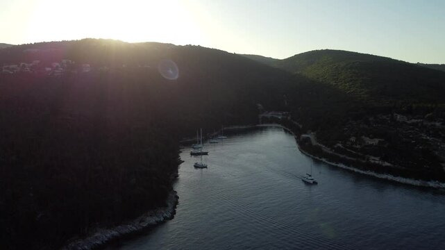 Aerial of the sailing boats anchored off the Foki Beach in Fiskardo, Kefalonia, Greece at sunset