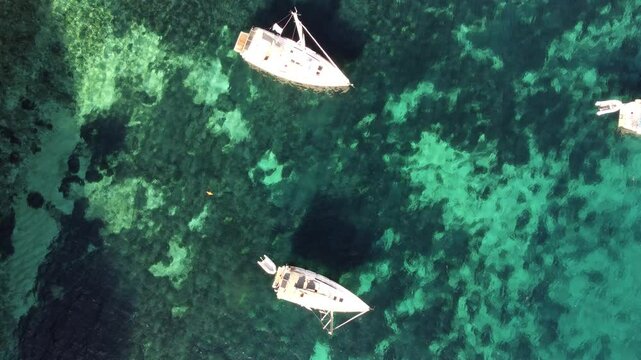 Top-down drone shot of the sailing boats anchored off the shore of the island of Atokos, Greece