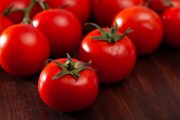 Juicy ripe tomatoes on natural wooden background. Vegetarian ingredient..