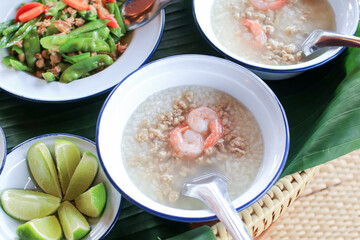 Boiled rice soup or porridge with shrimps in vintage metal white bowl. Thai style morning breakfast.