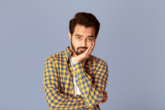 Handsome Indian man feeling bored or tired over lilac background