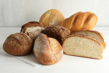 Whole and cut bread loafs on white table