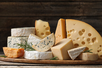 Different types of cheese and rosemary on wooden table