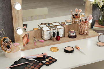 Makeup room. Different beauty products on white dressing table and mirror indoors
