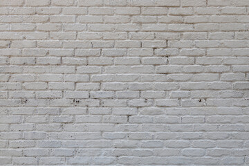 Full frame abstract texture background of a grungy white painted antique brick wall that shows some weathering and peeling paint