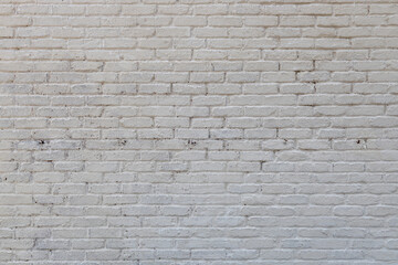 Full frame abstract texture background of a grungy white painted antique brick wall that shows some weathering and peeling paint