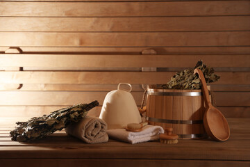 Bucket, whisks, massaging brushes and other equipment on wooden bench in sauna